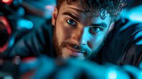 Young bearded man with intense blue eyes and curly hair in dramatic neon lighting, looking through creative foreground elements creating depth and atmosphere.