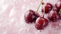Fresh red cherries with water droplets on ice crystals creating refreshing summer fruit display for beverage and dessert applications.