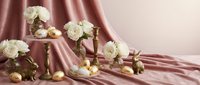 Elegant white roses and golden spheres arranged on luxurious pink silk fabric creating sophisticated still life composition for wedding decor and romantic events.
