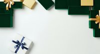 Wrapped gift boxes in emerald green and cream with gold and navy blue ribbons arranged on white background, ready for holiday design projects.