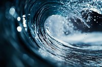 Ocean wave barrel with water droplets and foam creating dynamic motion blur effect. Natural seascape photography for surfing and marine sports content.