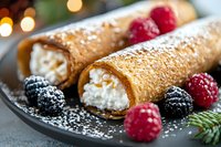 Homemade cannoli filled with sweet ricotta cream, dusted with powdered sugar and served with fresh raspberries and blackberries on dark plate. Food photography.
