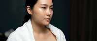 Professional Asian businesswoman in white blazer looking confidently away, corporate portrait for business presentations and marketing materials.