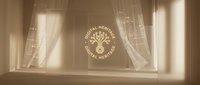 Sunlit window with sheer curtains and golden decorative emblem on glass, creating warm ambient light for interior design and home decor projects.
