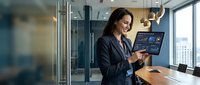 Professional businesswoman using digital tablet in modern office conference room with city view for corporate presentations and meetings.