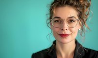 Young Caucasian businesswoman with curly updo hairstyle, red lipstick and round glasses smiling against turquoise background. Professional portrait for business and lifestyle.