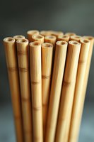 Natural bamboo drinking straws arranged in vertical composition against dark background, showcasing sustainable eco-friendly alternative to plastic straws.