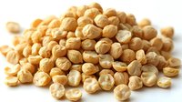 Dried chickpeas scattered on white background, macro view of raw garbanzo beans showing natural texture and patterns. Healthy protein-rich legumes for cooking.