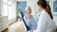 Senior Caucasian woman patient consulting with young female doctor in modern medical office during healthcare appointment.