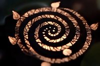 Glowing spiral pattern with delicate butterfly silhouettes arranged in circular motion against dark background creates mystical atmosphere for decorative designs.