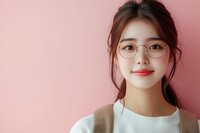 Young Asian woman wearing round glasses and white sweater smiling warmly against pink background, natural makeup and casual style for lifestyle and beauty content.