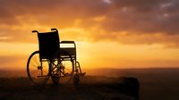 Silhouette of empty wheelchair against dramatic golden sunset sky with clouds, symbolizing hope, recovery, and overcoming challenges in healthcare and rehabilitation contexts.