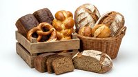 Assorted fresh baked bread loaves and rolls in wooden crate and wicker basket, including whole wheat, sourdough, and artisan varieties for bakery, food service, or culinary projects.