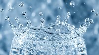 Water splash with droplets creating crown shape against blue background. Fresh liquid motion captured in high-speed photography for beverage and hydration concepts.
