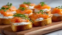 Appetizing smoked salmon canapes with cream cheese, fresh dill garnish, and toasted baguette slices arranged on wooden serving board, perfect for catering and events.