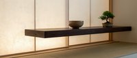 Minimalist Japanese interior with floating dark wood shelf, ceramic bowl, and bonsai tree against shoji screen wall with tatami floor.