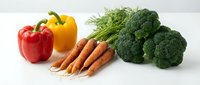 Fresh organic vegetables including red and yellow bell peppers, carrots with green tops, and broccoli florets arranged on white background for healthy cooking.