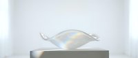 Transparent glass sculpture with iridescent rainbow reflections resting on a minimalist white pedestal in a bright studio setting.