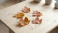Autumn maple leaves arranged on wooden table with soft natural lighting creating warm seasonal atmosphere for fall decorating and crafts.