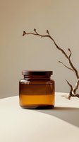 Amber glass jar with wooden lid alongside minimalist dried branch on beige background with soft shadows, modern aesthetic composition for cosmetic packaging.