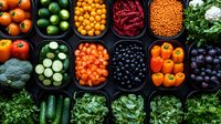 Fresh colorful produce in black containers including citrus, berries, peppers, leafy greens, legumes, and vegetables arranged in neat rows creating vibrant food pattern.
