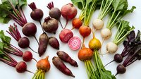 Fresh organic beetroot varieties with colorful roots and green leaves arranged on white background for healthy cooking and nutrition concepts.