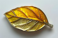 Golden autumn leaf brooch with detailed veining and metallic finish on light background, showcasing intricate jewelry craftsmanship and nature-inspired design.