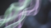 Colorful smoke swirls in green and purple tones against a dark background, creating an abstract, ethereal atmosphere.