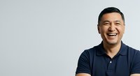 Asian male professional in his 30s wearing navy polo shirt, smiling confidently against neutral background. Suitable for corporate, business, and recruitment materials.