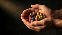 Adult male hands holding colorful crayons against dark background. Suitable for education, creativity, art supplies, and children's learning concepts.
