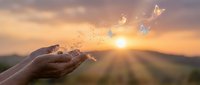 Hands releasing golden butterflies at sunset with warm light rays and mountain landscape background for freedom and transformation concepts.
