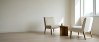 Minimalist interior with two beige chairs and wooden side table in bright room with natural light from large windows for modern home decor.