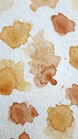 Abstract watercolor stains in warm earth tones on textured paper creating organic artistic background for creative projects and design work.