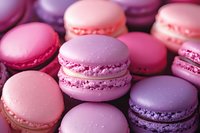 Colorful French macarons in shades of pink and purple with cream filling, arranged in rows showing delicate meringue texture and smooth round surfaces.