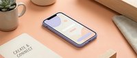 Modern smartphone mockup on minimalist wooden desk workspace with notebook and plant pot for branding presentation and app design showcase.