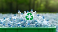 Empty plastic bottles with recycling symbol in green container, environmental waste management concept highlighting plastic pollution and sustainability solutions.