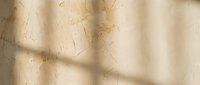 Aged beige concrete wall with scratches, dust, and shadow patterns creating texture for grunge backgrounds, overlays, or architectural design projects.