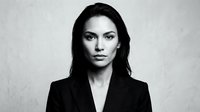 Professional businesswoman in black suit jacket with confident expression and dark hair against neutral background for corporate marketing materials.