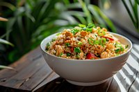 Fresh fried rice with vegetables, eggs and chicken garnished with green onions and sesame seeds in white ceramic bowl on wooden table, natural lighting.