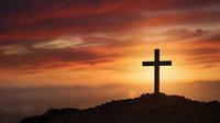 Silhouette of wooden cross on rocky hill against dramatic orange sunset sky with clouds for spiritual and religious themes.