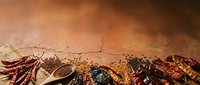 Dried red chili peppers and spices arranged on cracked earth texture background for culinary and cooking design projects.