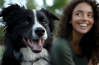 Happy Border Collie dog with tongue out sitting next to smiling young mixed-race woman outdoors. Pet ownership, companionship and friendship concept.