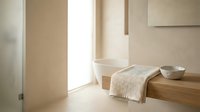 Minimalist bathroom interior with wooden vanity, folded towel, and ceramic bowl, featuring bright natural light from window and neutral beige tones for spa and wellness design projects.