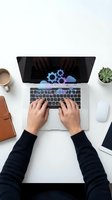 Hands typing on laptop with cloud computing gears on screen, modern workspace with coffee cup, plant and leather bag on white desk for business technology.