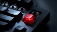 Red translucent enter key stands out on dark computer keyboard in dramatic lighting creating striking contrast for technology concepts.