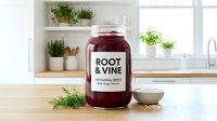Root and vine artisanal waste fermented beverage in glass jar displayed on kitchen counter with fresh herbs and shelving, ready for culinary use.