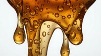 Amber liquid with bubbles dripping down on white background, isolated for design use on packaging, advertising, cosmetics, skincare products, and beverage marketing materials.