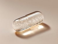Transparent capsule filled with sparkling silver particles floating in clear liquid against soft beige background, casting golden shadow beneath. Medical and pharmaceutical concept.