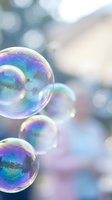 Colorful soap bubbles floating with rainbow reflections against soft blurred background. Dreamy bokeh effect creates magical atmosphere for relaxation concepts.