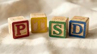 Wooden alphabet blocks spelling POSD in red, yellow, green, and blue colors arranged on neutral fabric background for educational and developmental learning concepts.